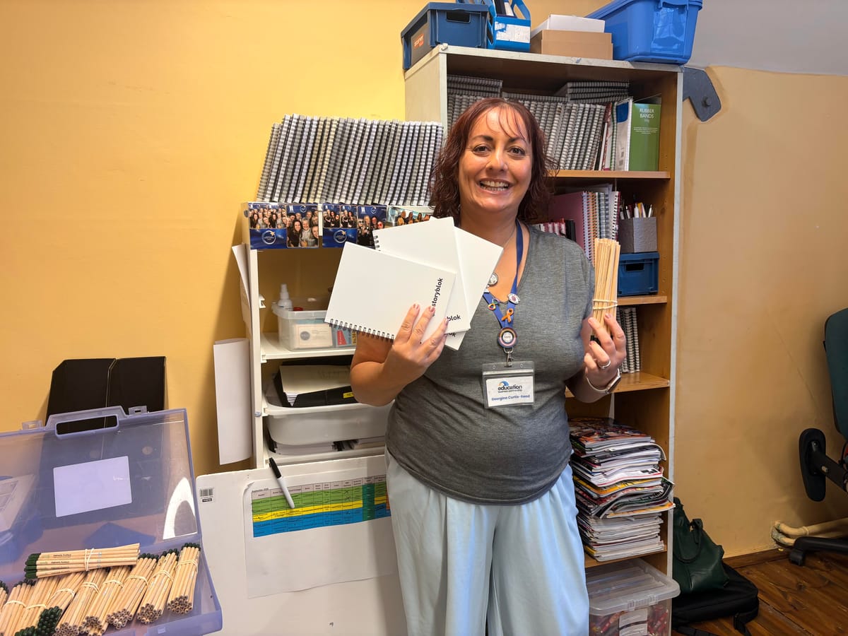 A member of staff at EBP holding donated notebooks and pencils